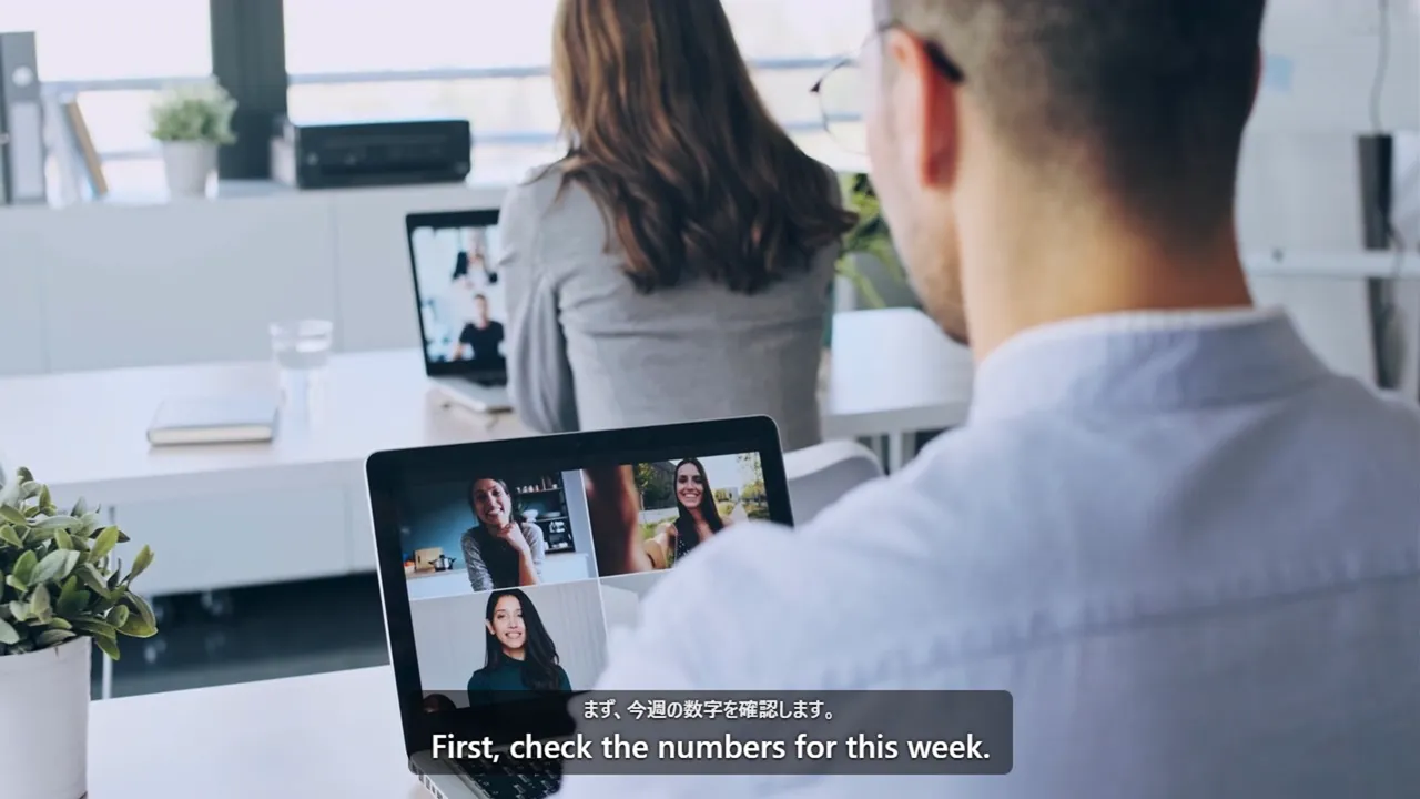 A video call on a laptop, with the Japanese line and its English subtitle shown over it