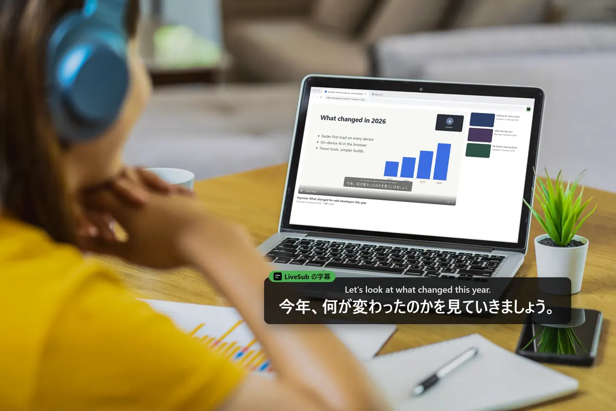 ヘッドホンをした人がノートパソコンで英語の講演を聞いていて、日本語の字幕が出ている